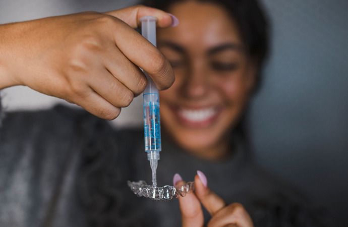 Woman pouring a transparent paste into her teeth mould